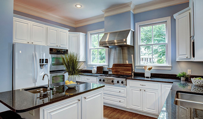 A blue kitchen with a stove, refrigerator, sink, and microwave.