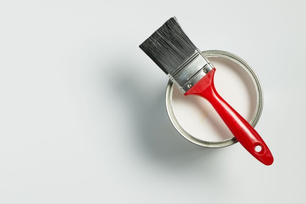 A paint brush and can of paint on white background - ideal for cabinet painters and refurbishing services