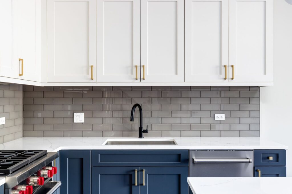 A modern kitchen featuring blue cabinets and white countertops, showcasing professional cabinet painting craftsmanship.