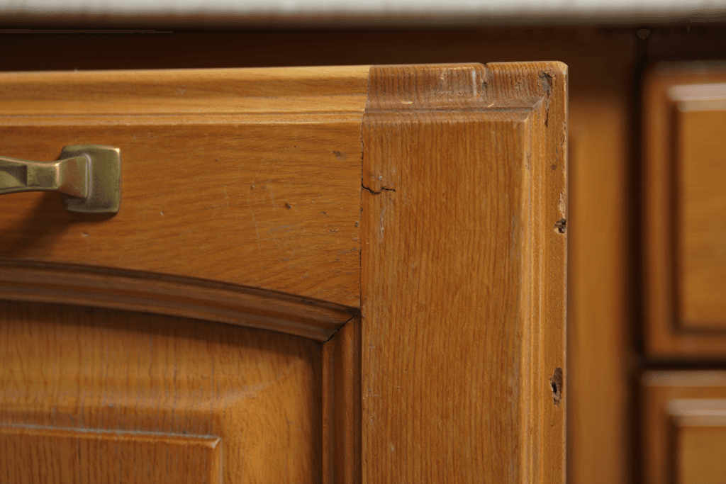 The Ultimate Guide to Restoring Wood Cabinets to Their Former Glory Right in Your Utah Home 1 Close-up of a solid wood cabinet with a chipped and yellowed finish, an ideal candidate for professional kitchen cabinet restoration instead of replacement.