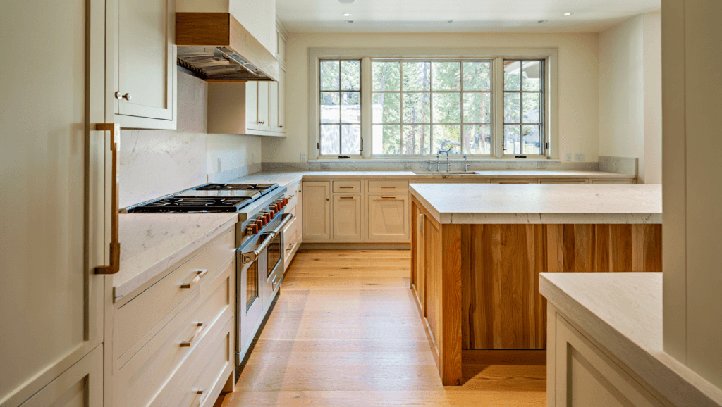 Bright mountain-modern kitchen featuring creamy white cabinetry and natural wood accents, illustrating the shift toward warmer 2025 kitchen cabinet colors
