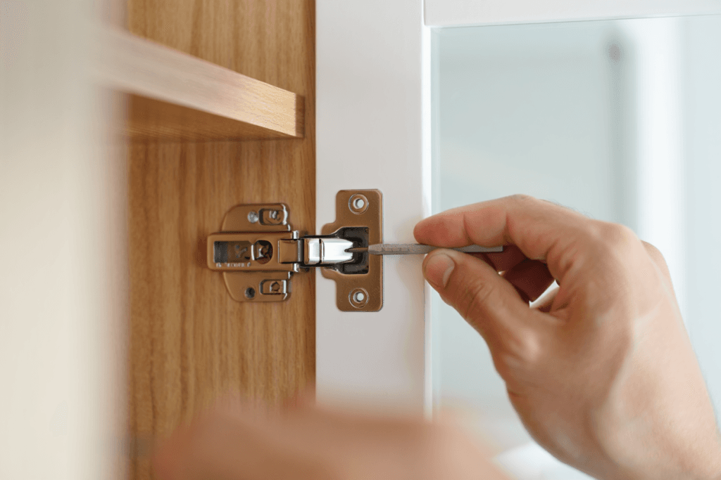 5 Signs Your Kitchen Cabinets Need Refinishing 3 homeowner inspecting a sturdy cabinet hinge and wooden frame