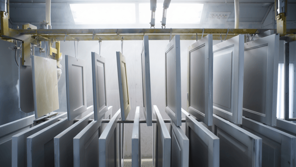 Kitchen Cabinet doors receiving 2K polyurethane finish in a professional spray booth for high-quality kitchen cabinet painting.