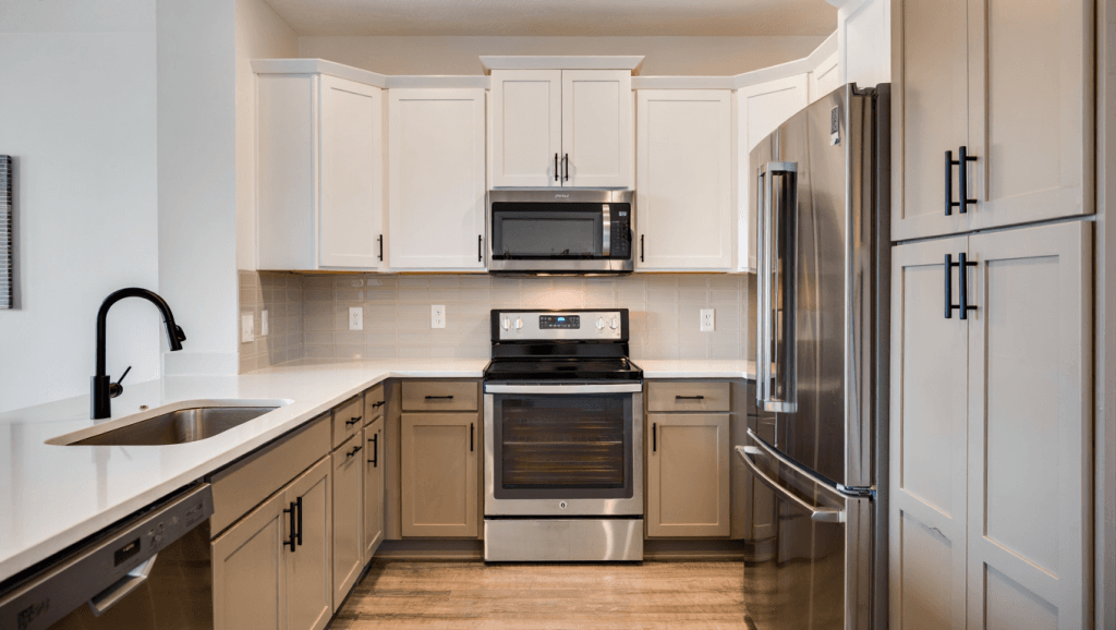 Two-tone Utah kitchen with greige lower cabinets, white uppers, quartz counters, and matte black fixtures.