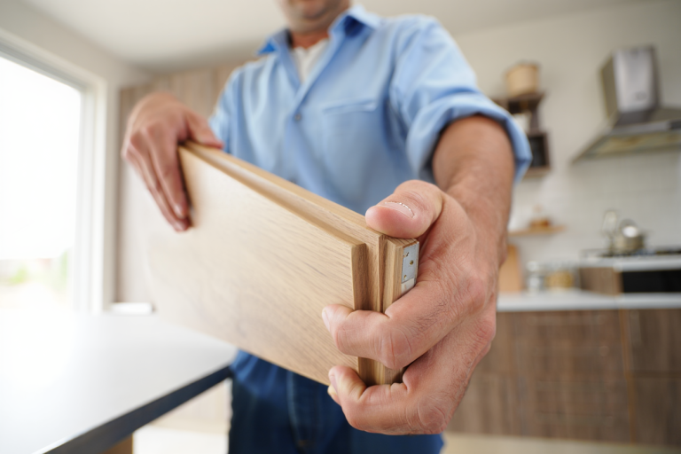 Cabinet painter inspecting kitchen cabinet door construction and wood condition
