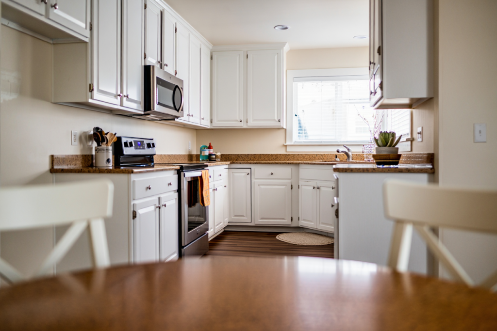 Neutral painted kitchen cabinets in a Utah home prepared for real estate listing, warm white and white two-tone finish